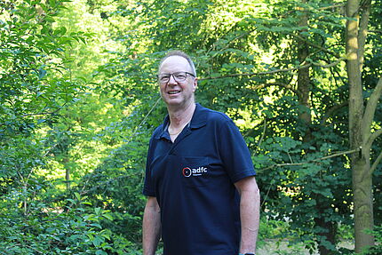 Zu sehen ist Holger Beuth im dunkelblauen ADFC-Poloshirt vor einem Wald im Hintergrund